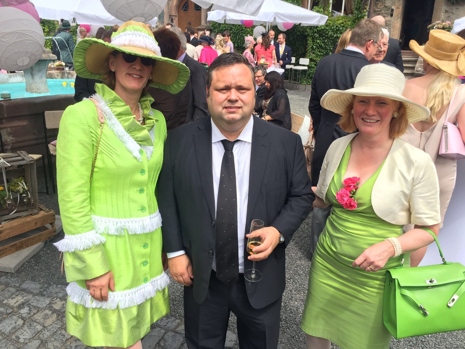 “ Anna v.S. in einem Edle von Zwirn Bolero und Charlotte v.C. in einem Edle von Zwirn Mantelkleid mit Hut umrahmen den britischen Castingstar Paul Potts auf einem Hochzeitsempfang 2016.“